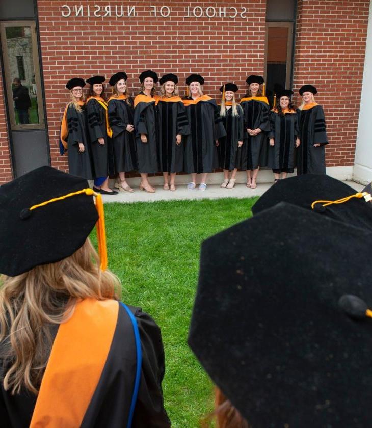 Nursing DNP grads 2022 outside CONHS in gowns and hoods 